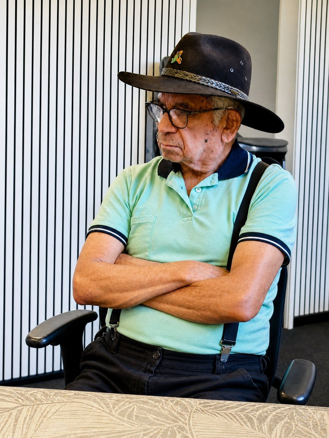 Uncle Bill Lemson seated with his arms folded, listening intently in his black hat and glasses