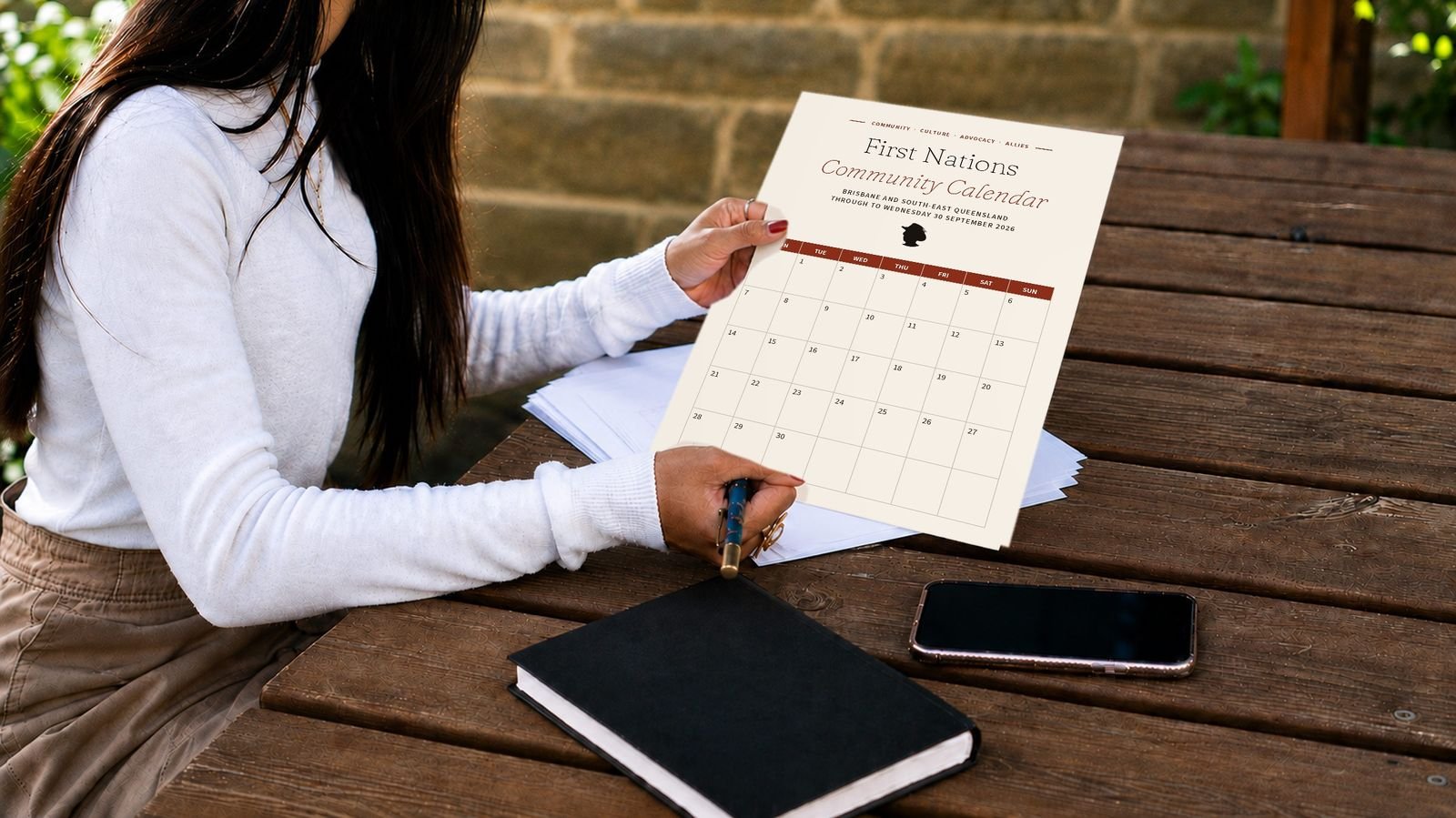 A woman holding a printed First Nations Community Calendar page