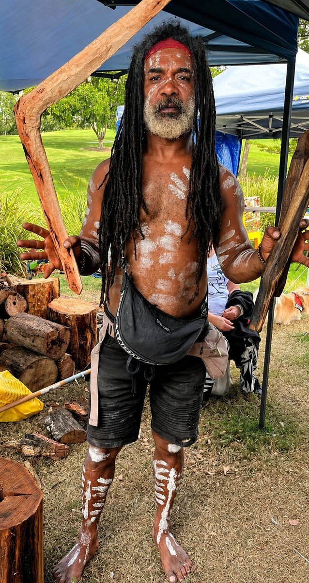 Uncle Derek &lsquo;Powder&rsquo; Oram standing in ceremonial body paint, holding traditional implements.
